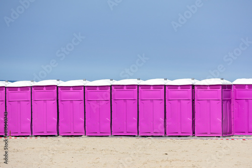Row of pink portable chemical public toilets on beach