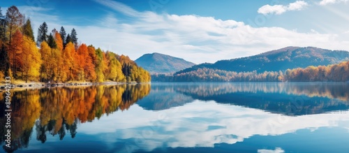 Picturesque autumn landscape view with colorful trees reflecting in the blue lake and mountain backdrop suitable for copy space image