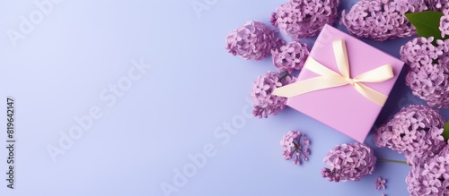 Top view of lilac flowers arranged in a frame with a gift box on a blue background suitable for Mother s Day with copy space image photo