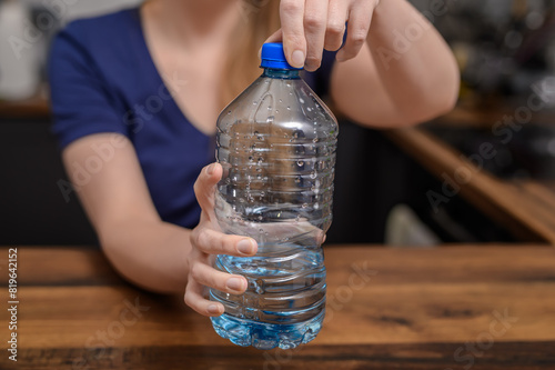 Kobieta odkręca butelkę plastikowa z wodą mineralną