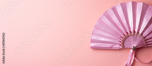 Top view of a closed Japanese handheld fan in its small bag a stylish fashion accessory displayed against a pink background with copy space image