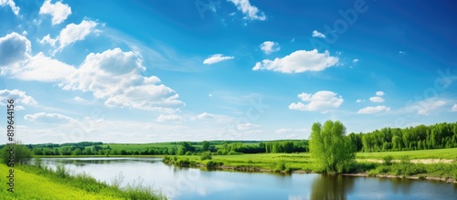 A spring landscape with a river trees silhouetted against the horizon set against a clear blue sky adorned with fluffy white clouds creating an ideal copy space image