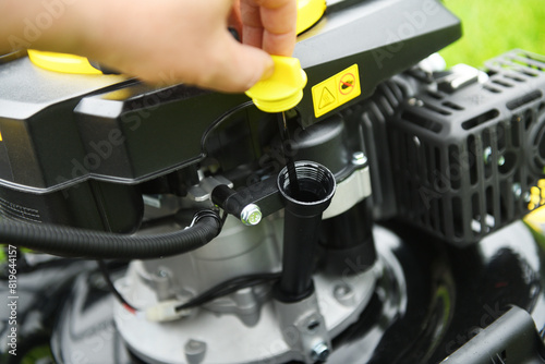 A worker checks the oil level in a new lawn mower. Checking the oil in the lawn mower. Maintenance.
