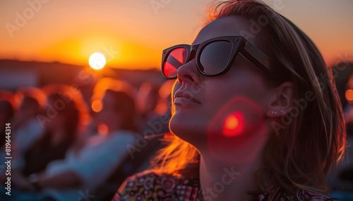 A group of people wearing sunglasses watching the sunset at an outdoor cinema