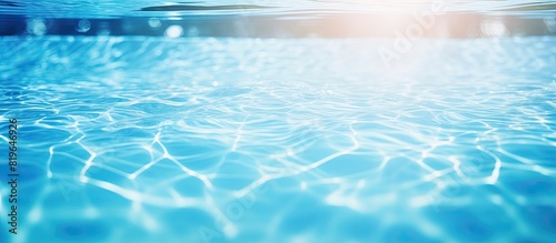 Close up background of a swimming pool with a blue water surface reflecting bright sunlight in the copy space image
