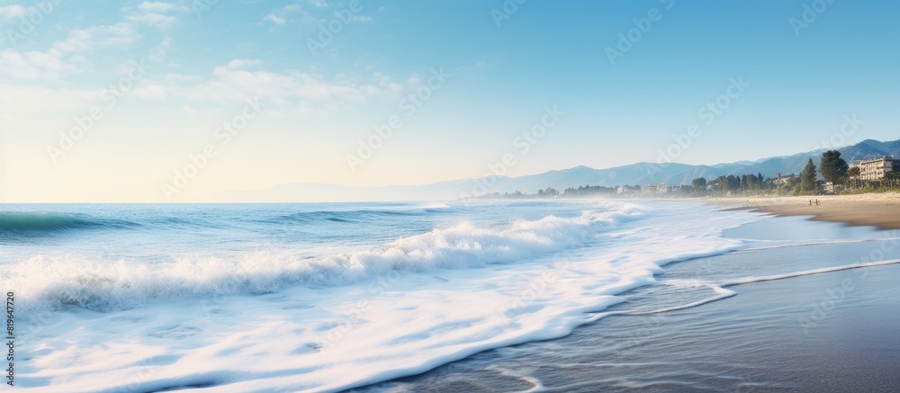 Waves crashing onto the seashore with a clear sky and a stunning beach setting creating a scenic copy space image