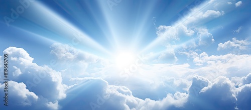 Bright sun rays beaming through fluffy clouds in a clear blue sky creating a picturesque scene with copy space image