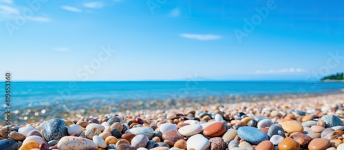 Beach pebbles scattered on the serene seashore with a clear sky providing a tranquil background for your copy space image
