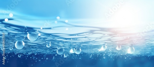 A trendy abstract nature background featuring defocused transparent blue water with splashes bubbles and waves glistening in sunlight perfect for a copy space image