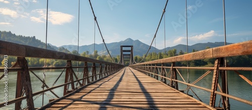 On a sunny summer day a distant view of an old wooden bridge suspended by iron ropes contrasts with a modern metal bridge across the Katun River both under a clear sky with copy space image photo