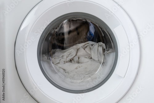 Close-up laundry running washing machine at home, amid a washing cycle, home electronics concept