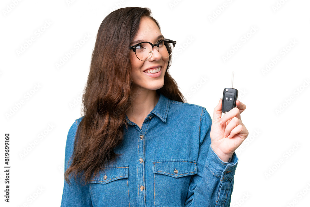 Young caucasian woman holding car keys over isolated background looking up while smiling Young caucasian woman holding car keys over isolated background looking up while smiling