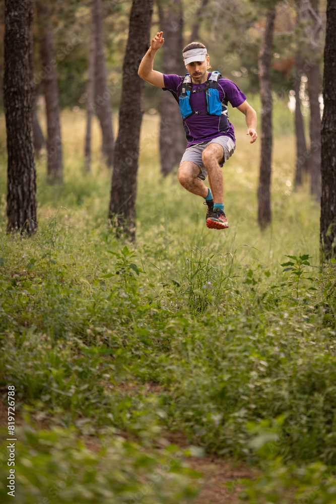 A man is jumping over a grassy field. He is wearing a purple shirt and blue shorts A man is jumping over a grassy field. He is wearing a purple shirt and blue shorts