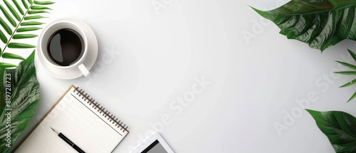 Minimalist workspace with a notepad, coffee cup, tablet, and green leaves on a white background, perfect for business or creative settings