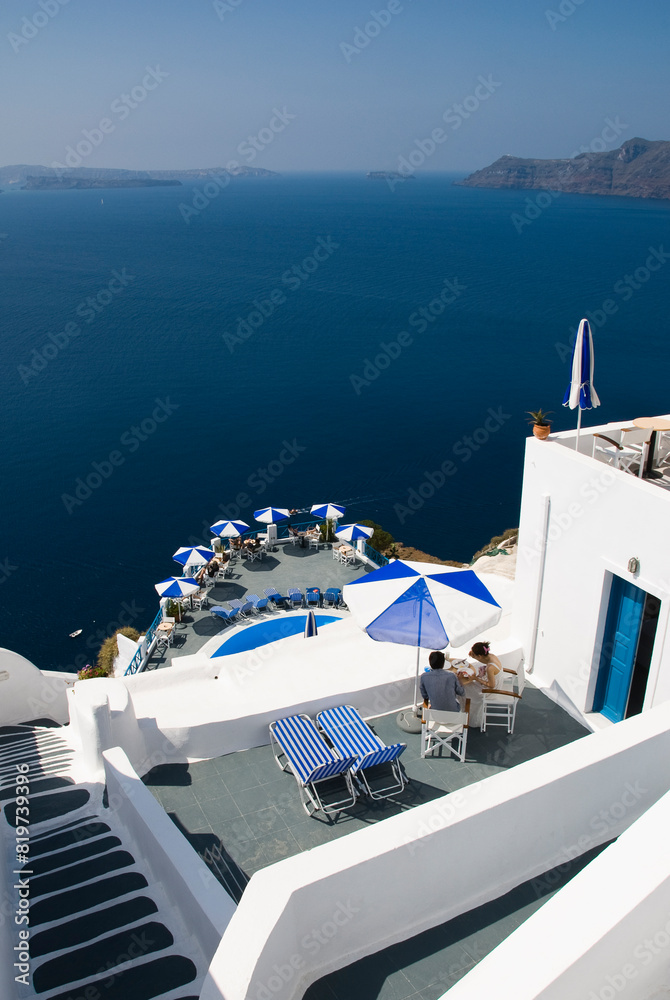 Obraz premium Terrace with chairs and umbrellas overlooking the waterfront in Santorini, Greece.