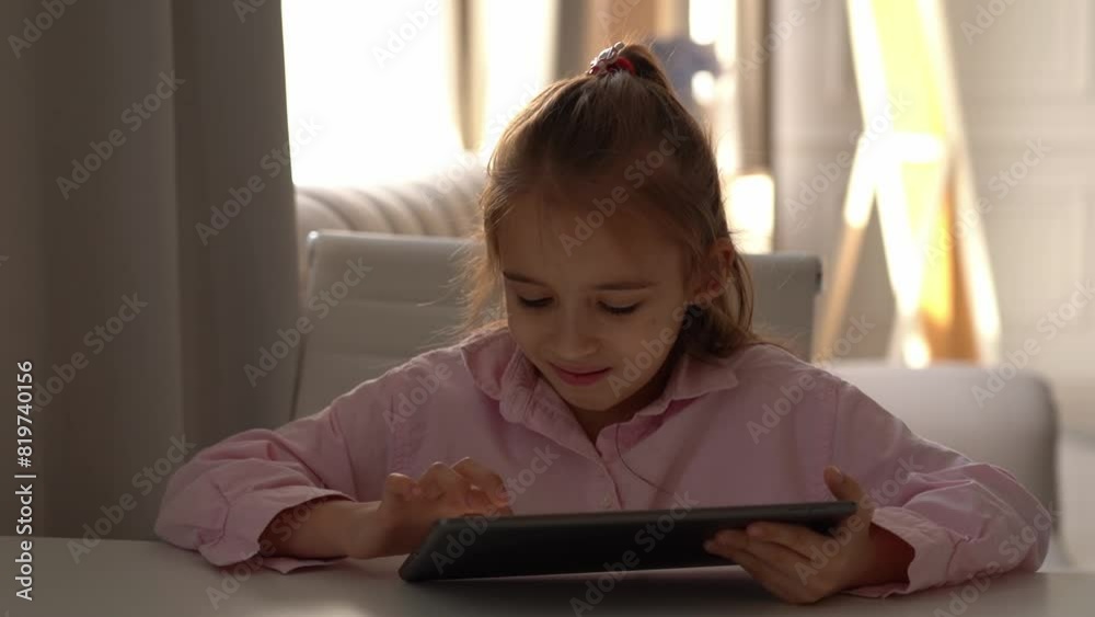 Happy Girl Using Tablet. Intensely focused on a gadget. Caucasian school girl Engaged With Tablet in Bright Living Room During Daytime Happy Girl Using Tablet. Intensely focused on a gadget. Caucasian school girl Engaged With Tablet in Bright Living Room During Daytime