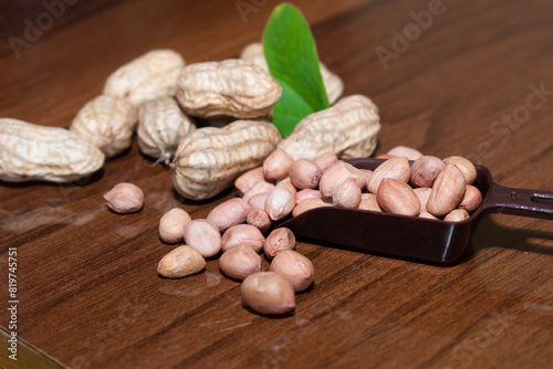 Fresh peanuts and leaves in bowl on wooden table