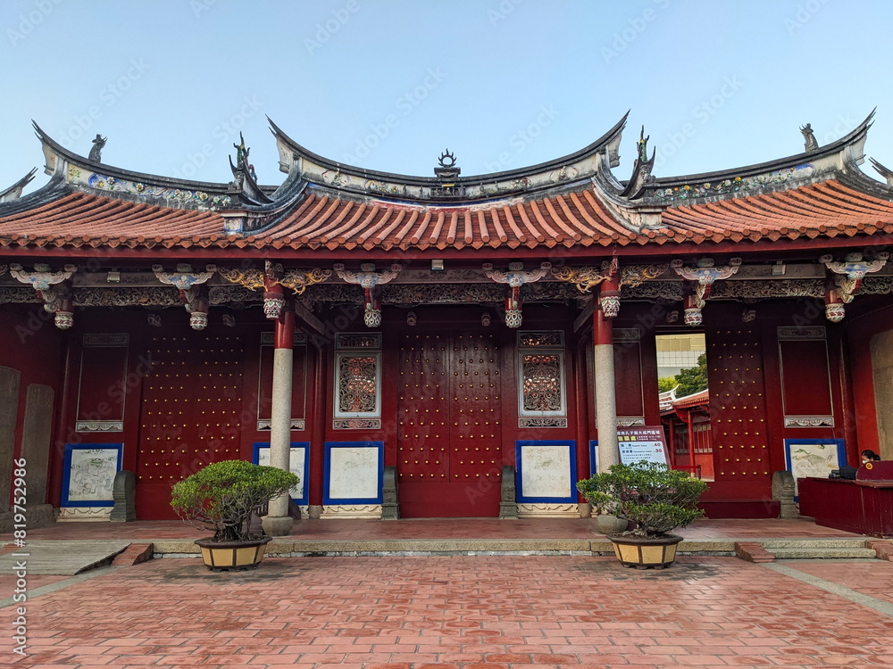 Tainan, Taiwan - 11.29.2022: Entrance to the main area of Tainan Confucius Temple with tiled roof and a ticket stall and a staff member on the right hand side under a blue sky during the pandemic Tainan, Taiwan - 11.29.2022: Entrance to the main area of Tainan Confucius Temple with tiled roof and a ticket stall and a staff member on the right hand side under a blue sky during the pandemic