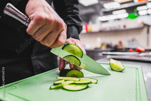 Close-up of hands slicing a cucumber on a green cutting board