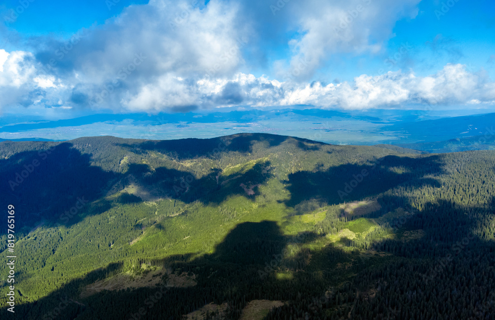 Fototapeta premium Aerial view with the shadows of the clouds on the mountains. Gurghiu mountains seen from above