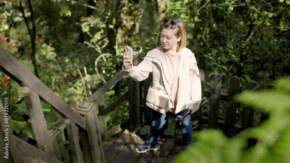 Slow motion of an Asian woman taking videos of green trees on the staircase Slow motion of an Asian woman taking videos of green trees on the staircase