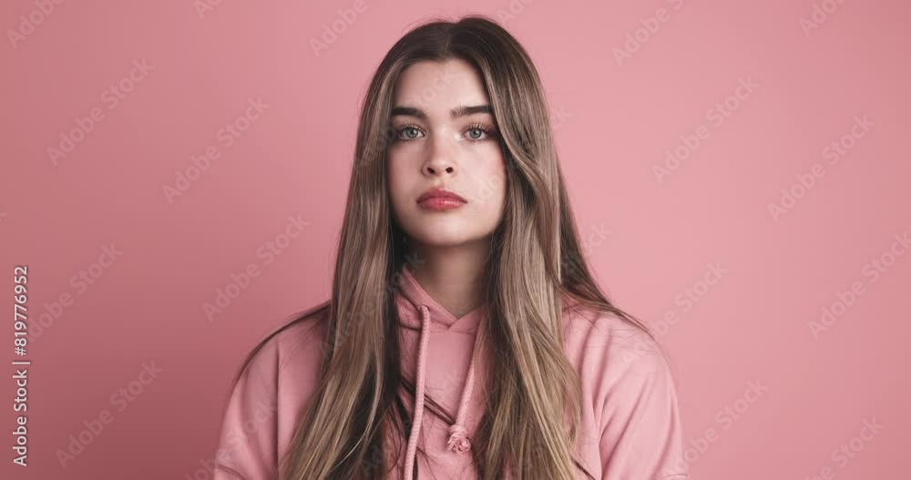 Upset young woman with long hair against pink wall
