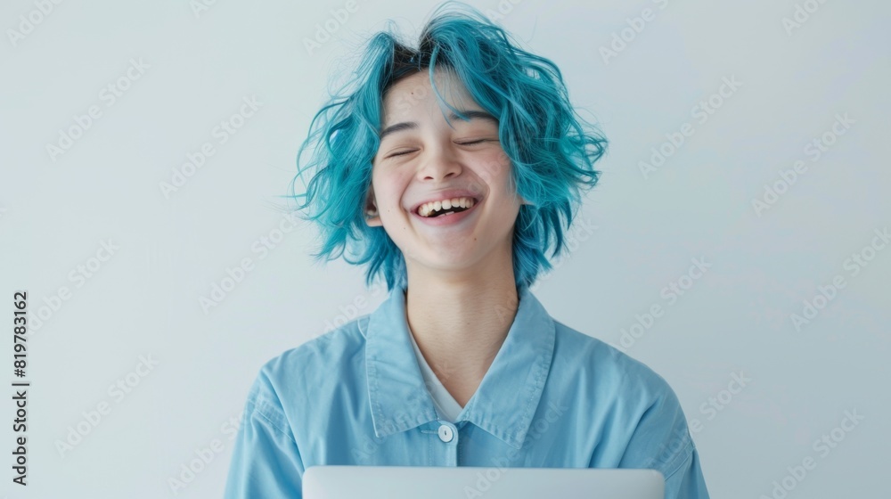 Obraz premium Cheerful Teenage Student with Blue Highlights Laughing While Holding Laptop in Blue Uniform against White Background