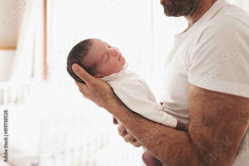 Tender father-baby embrace in soft white clothing photo