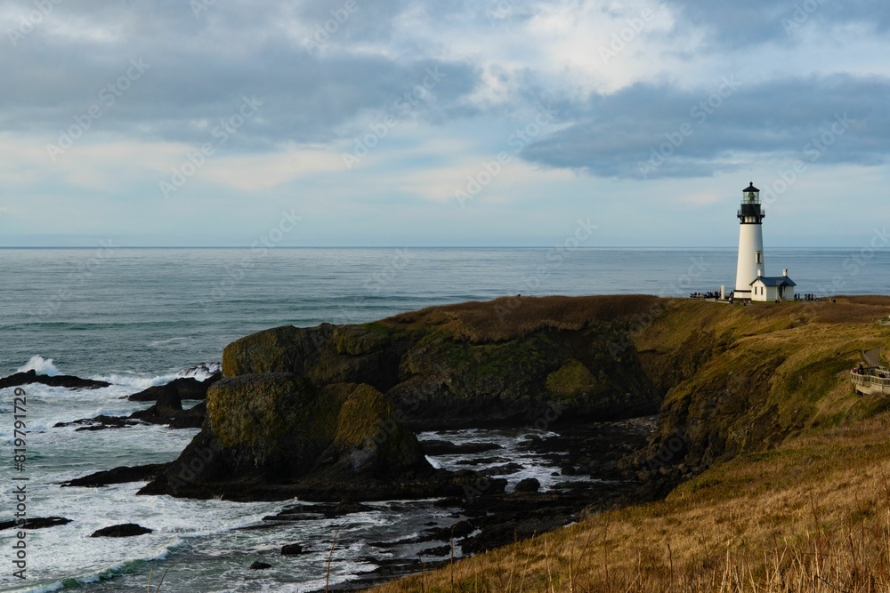 White lighthouse on the coast against the cloudy sky in summer White lighthouse on the coast against the cloudy sky in summer