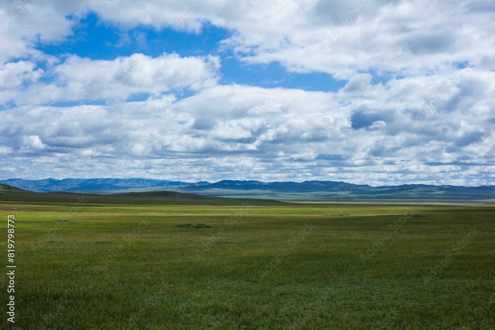 Scenic landscape featuring rolling fields with a few scattered clouds in the sky Scenic landscape featuring rolling fields with a few scattered clouds in the sky