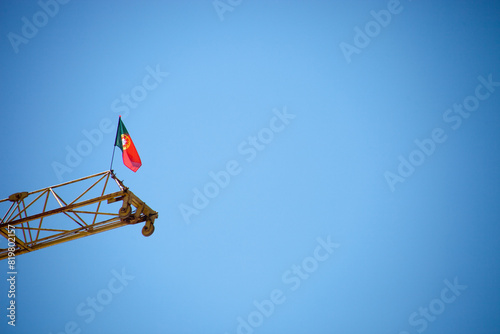 Фотография Portuguese flag waving atop a crane, symbolizing progress and national pride