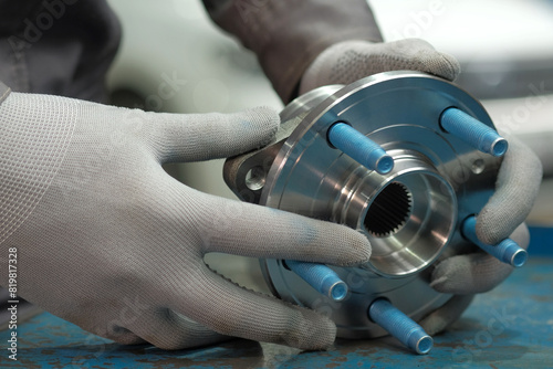 Car parts.The wheel hub is rear.An auto mechanic holds a new hub in his hands, checks the part before replacing it. Repair and maintenance at the service center.