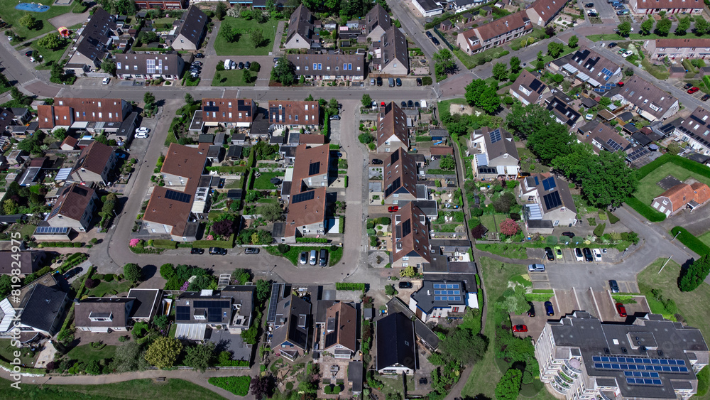 Naklejka premium Aerial shot of houses with solar panels on roof in a street in a residential area neighborhood in Holland.