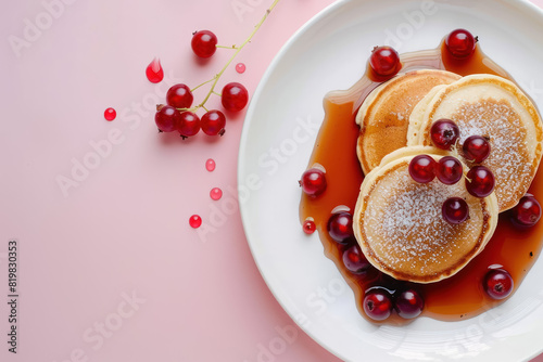 pancakes with red currants and flowing syrup on pink background
