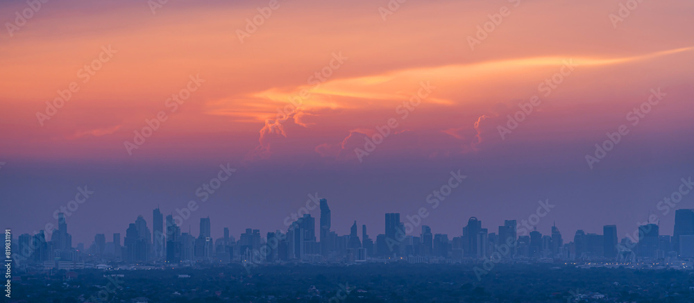 Fototapeta premium Sunrise over modern office buildings in district center of Bangkok. Panoramic skyline view of cityscape with sunlight and flare in warm light color tone. Construction business concept.