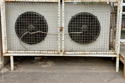 Two refrigeration fans for industrial cold rooms of supermarket. Air coolers refrigeration evaporators installed on ground have metal wire crate, closed doors with hinged metal lock for maintenance