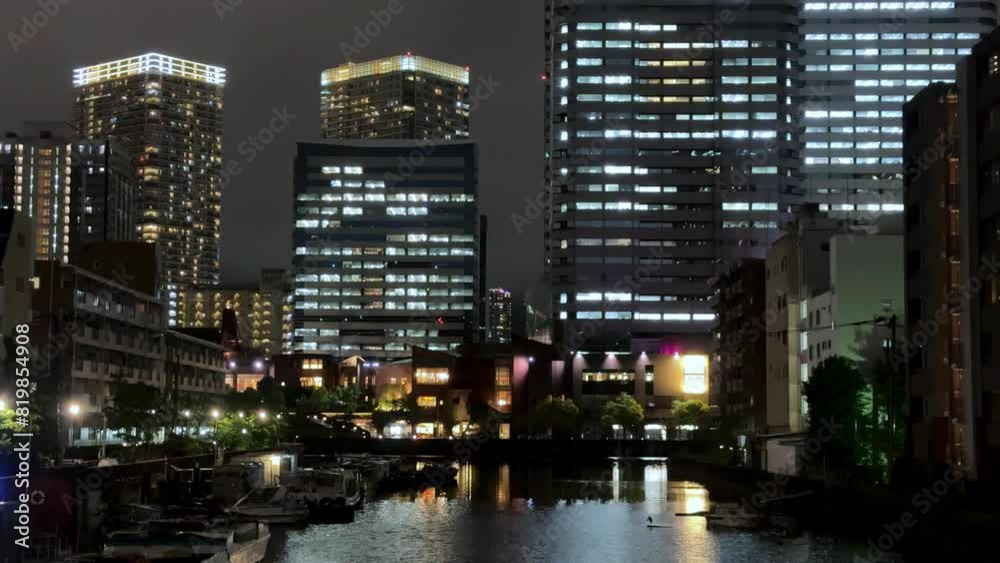 Night view of a cityscape with illuminated skyscrapers reflected in a calm river Night view of a cityscape with illuminated skyscrapers reflected in a calm river