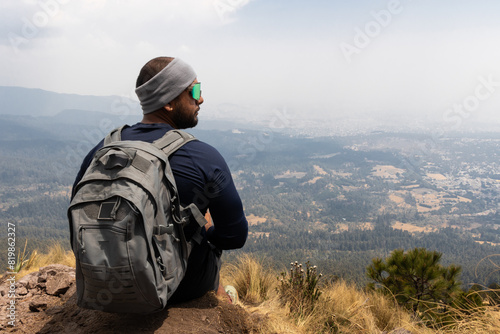 Hiker resting on a mountaintop overlooking valley photo