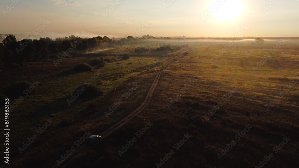 The car is driving along a country road at dawn The car is driving along a country road at dawn