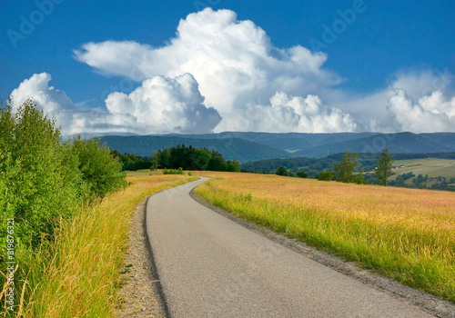 Country asphalt road and rural summer landscape in the Low Beskids, Oderne, Poland