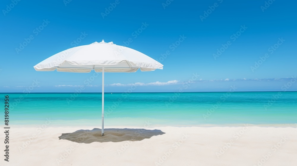 Deserted beach umbrella casting shadow on white sand and crystal clear blue water
