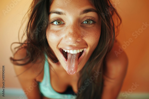 Charming woman humorously sticks out her tongue, creating a funny expression photo