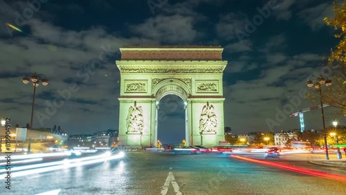 4K Timelapse of traffic at Arc de Triomph at night. This historical monument overlooks the avenue des champs élysées in the heart of Paris, French capital. photo