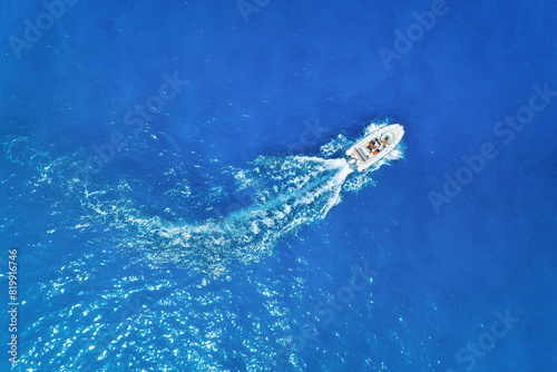 Aerial view on fast boat on blue sea at sunny day. Vacation and leisure. Fast ship on the sea surface. Seascape from the drone. Seascape with motorboat.