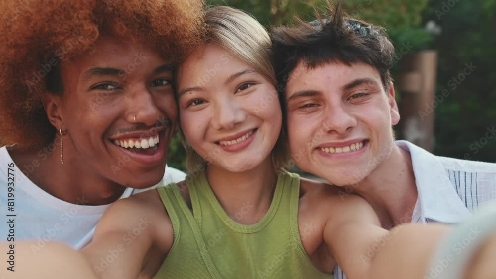 Close-up of three joyfull friends taking pictures selfies on the street, smiling at the camera Close-up of three joyfull friends taking pictures selfies on the street, smiling at the camera