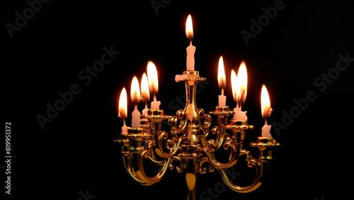 Close-up of rotating candelabra with white burning candles isolated on black. photo