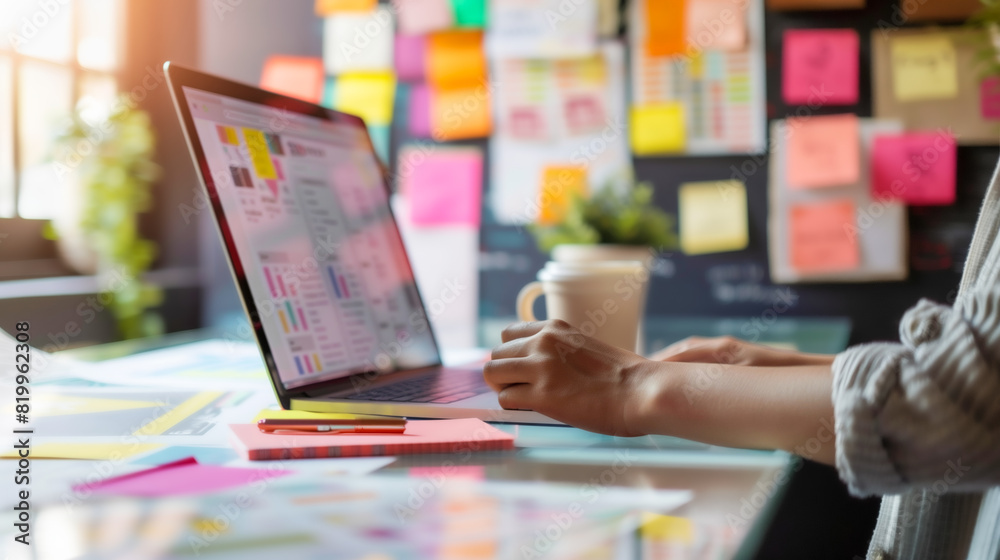 A freelancer works on a laptop, brainstorming ideas in a creative workspace with energy and dynamic and productive work environment. Blurred background, sticky notes with reminder messages on board. A freelancer works on a laptop, brainstorming ideas in a creative workspace with energy and dynamic and productive work environment. Blurred background, sticky notes with reminder messages on board.