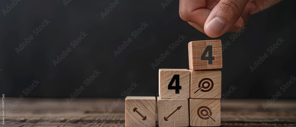 A hand placing a wooden block labeled with the number 4 on top of a stack of wooden blocks arranged in ascending order The blocks feature arrows and targets A hand placing a wooden block labeled with the number 4 on top of a stack of wooden blocks arranged in ascending order The blocks feature arrows and targets