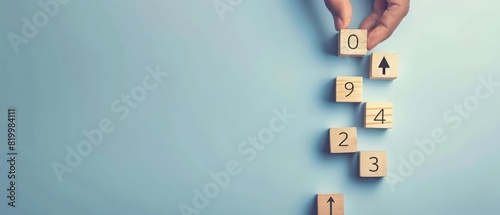 A top view of a hand arranging wooden blocks labeled with numbers and arrows in ascending order on a clean