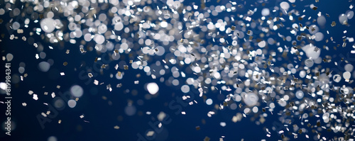 Sparkling silver confetti descending against a deep blue backdrop, creating a joyous ambiance.